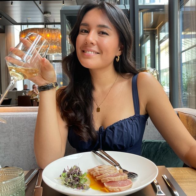 Creator brinda com uma taça de vinho diante de um prato de atum selado